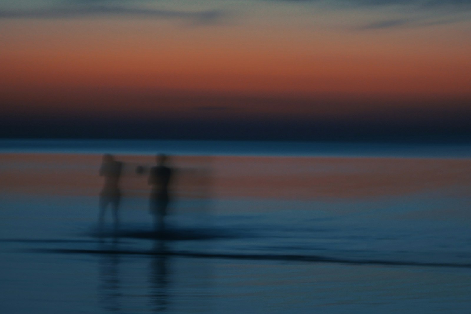 A couple of people standing on top of a beach